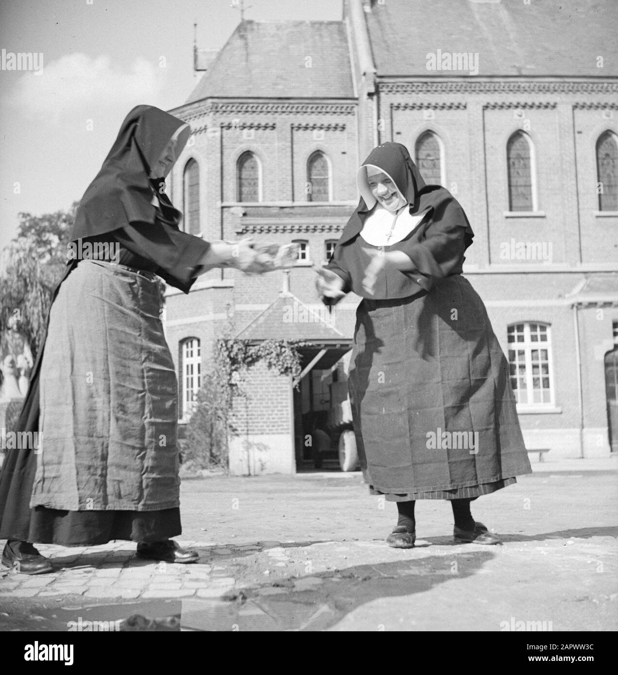 Rebuilding a nunnery  Nuns give each other stones by Date: 1940 Location: France Keywords: bricks, monasteries, nuns Stock Photo