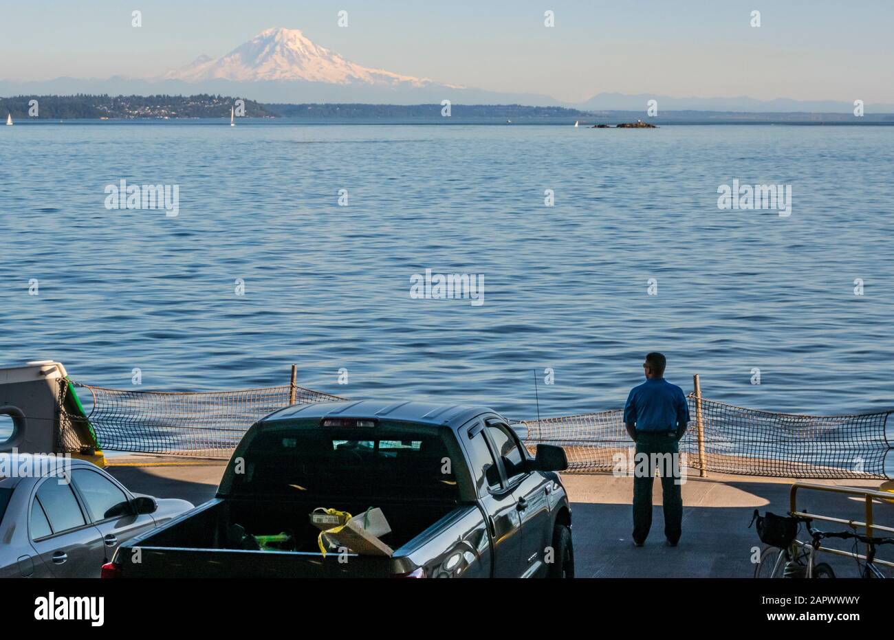 A man stands on the car deck of a Washington State Ferry looking out at the scenery. Stock Photo