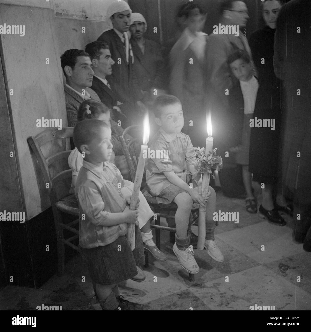 Israel 1948-1949: Galilee  Easter Miss in the Basilica of the Annunciation in Nazareth with the face of the churchgoers including two children with a burning candle in hand Date: 1948 Location: Israel, Nazareth Keywords: candles, church buildings, children, liturgy, religious services, religious holidays Stock Photo