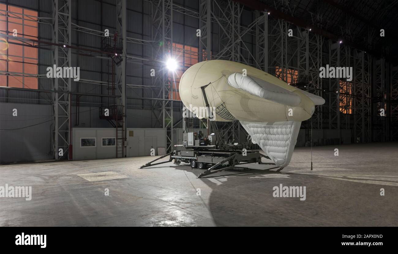 Small airship on a mooring platform in a giant aircraft hangar Stock Photo