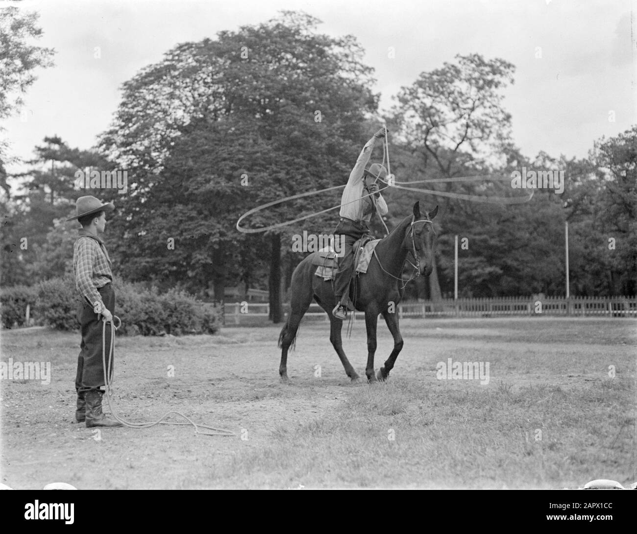 Wakanda Club Paris 1936 - Indians shows  Paul Cozé on horseback with spinning lasso; a cowboy stands next to Date: May 1936 Location: France, Paris Keywords: cowboys, horses Person name: Cozé, Paul Stock Photo