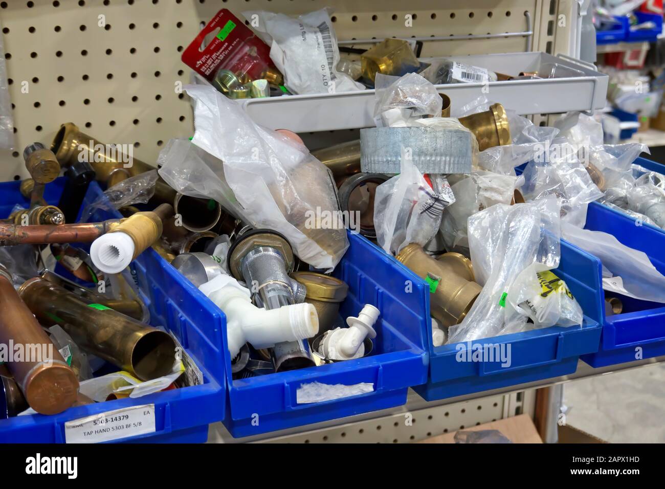 Misc. copper and brass fittings in blue bins on display in a hardware store. Stock Photo