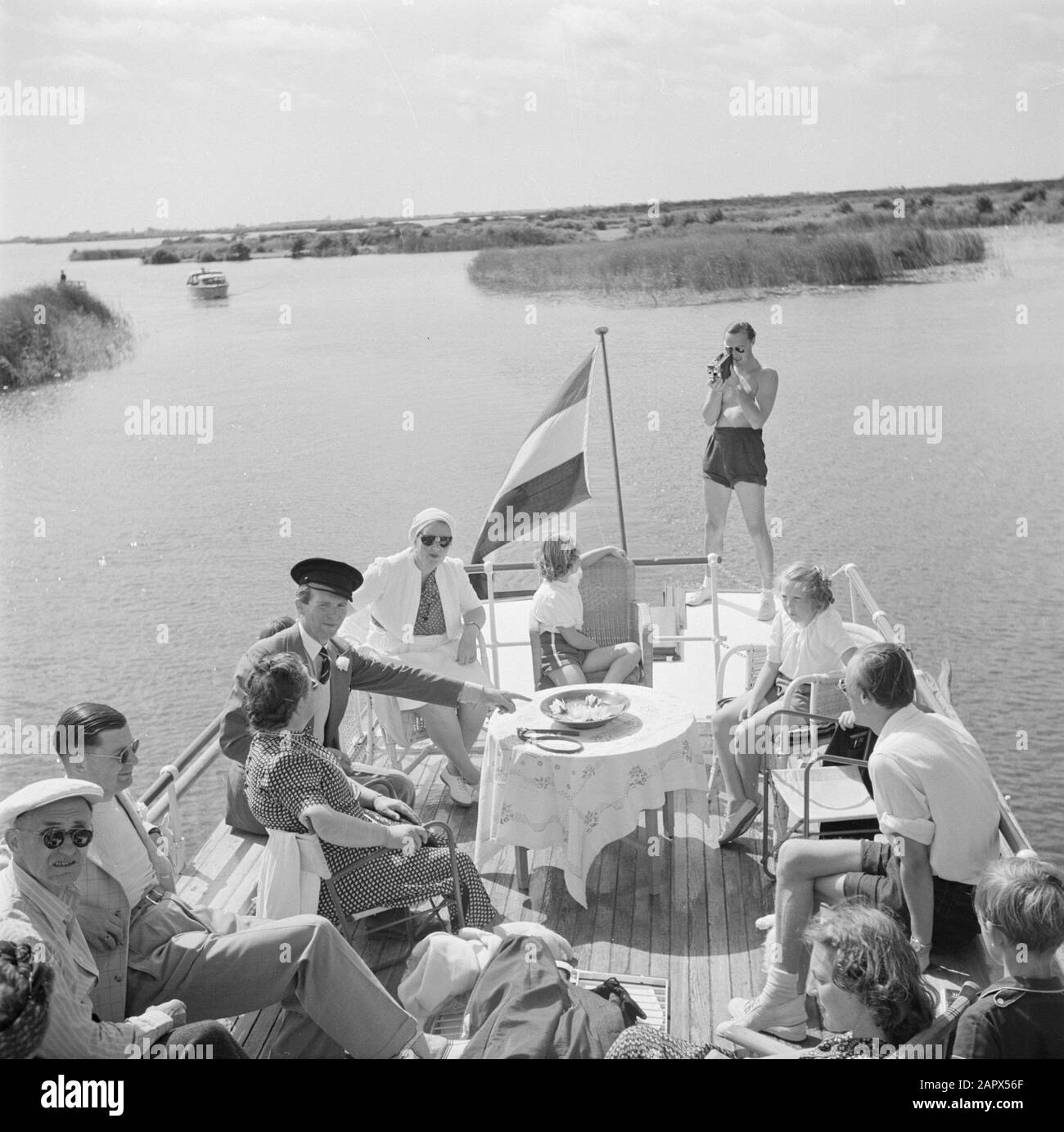 The princely family in Friesland  Princess Juliana, Princess Beatrix, Princess Irene, Nanny Rita Pennink and others on the aft deck of a ship. Prince Bernhard films the company Date: 1947 Location: Friesland Keywords: film cameras, royal house, princesses, princesses, ships, sun decks Personal name: Beatrix, princess, Bernhard, prince, Irene, princess, Juiana, princess Stock Photo