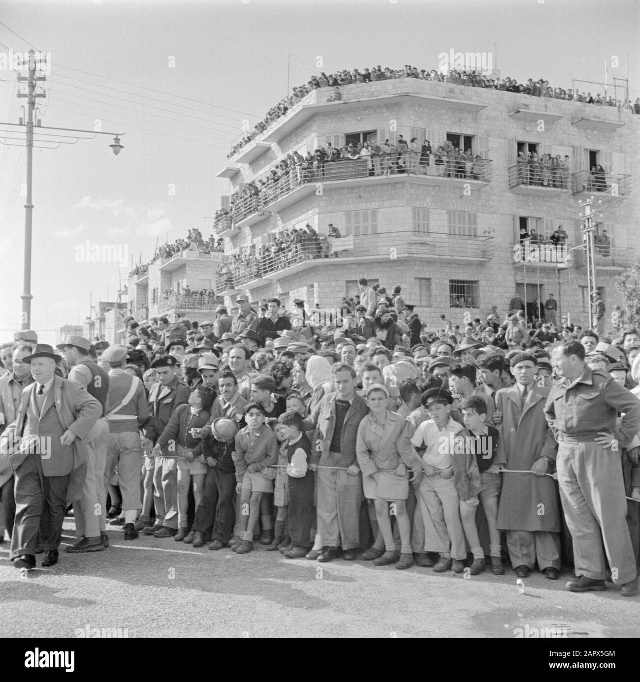 Israel 1948-1949: Haifa  Audience and a police officer during the military parade in Haifa on the occasion of the first anniversary of Israel's independence on May 15, 1949 Date: May 15, 1949 Location: Haifa, Israel Keywords: architecture, military parades, national holidays, police officers, public, uniforms Stock Photo
