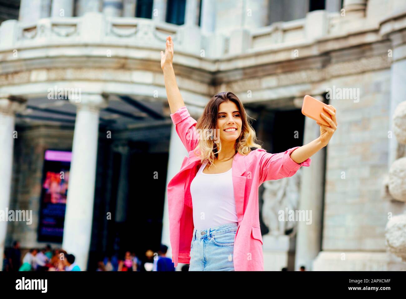Outdoor portrait of a young woman taking a selfie in front of a ...