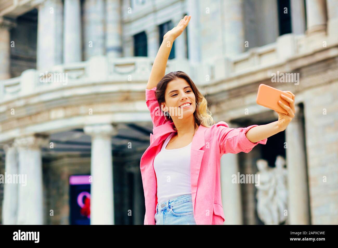 Outdoor portrait of a young woman taking a selfie in front of a ...
