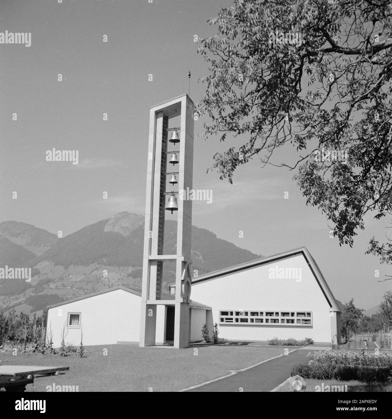 Modern, reformed church building in a Swiss village in the mountains  Schwyz. Church of the Evangelical-reformierte Kirchengemeinde Brunnen-Schwyz: entrance part of the church building with side spaces and the bell tower Date: 1 January 1950 Location: Schwyz, Switzerland Keywords: architecture, mountains, Calvinism, church buildings, church towers, bells Stock Photo