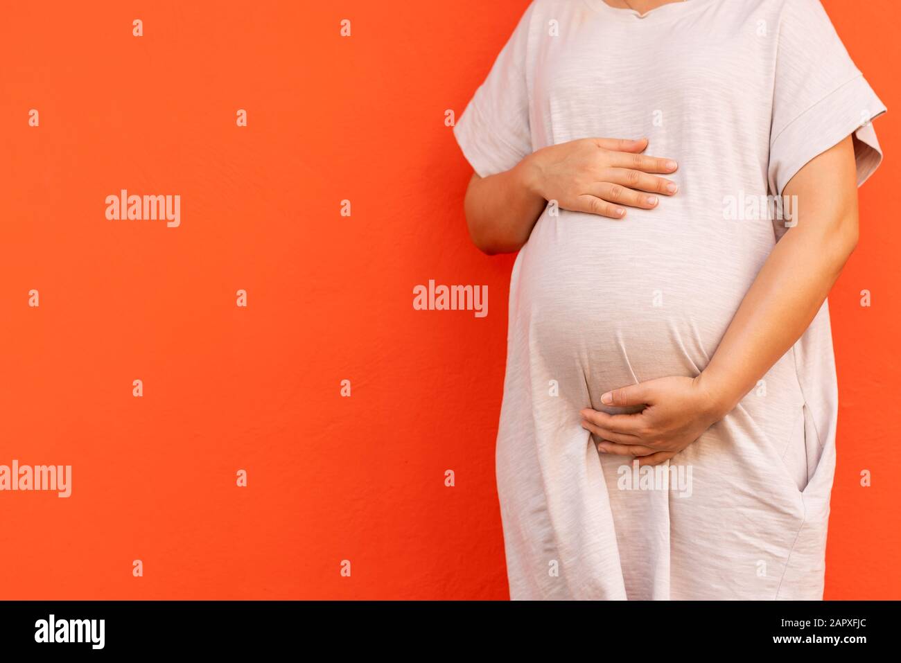 Pregnant woman feeling happy at home while taking care of her child. The young expecting mother holding baby in pregnant belly. Maternity prenatal car Stock Photo