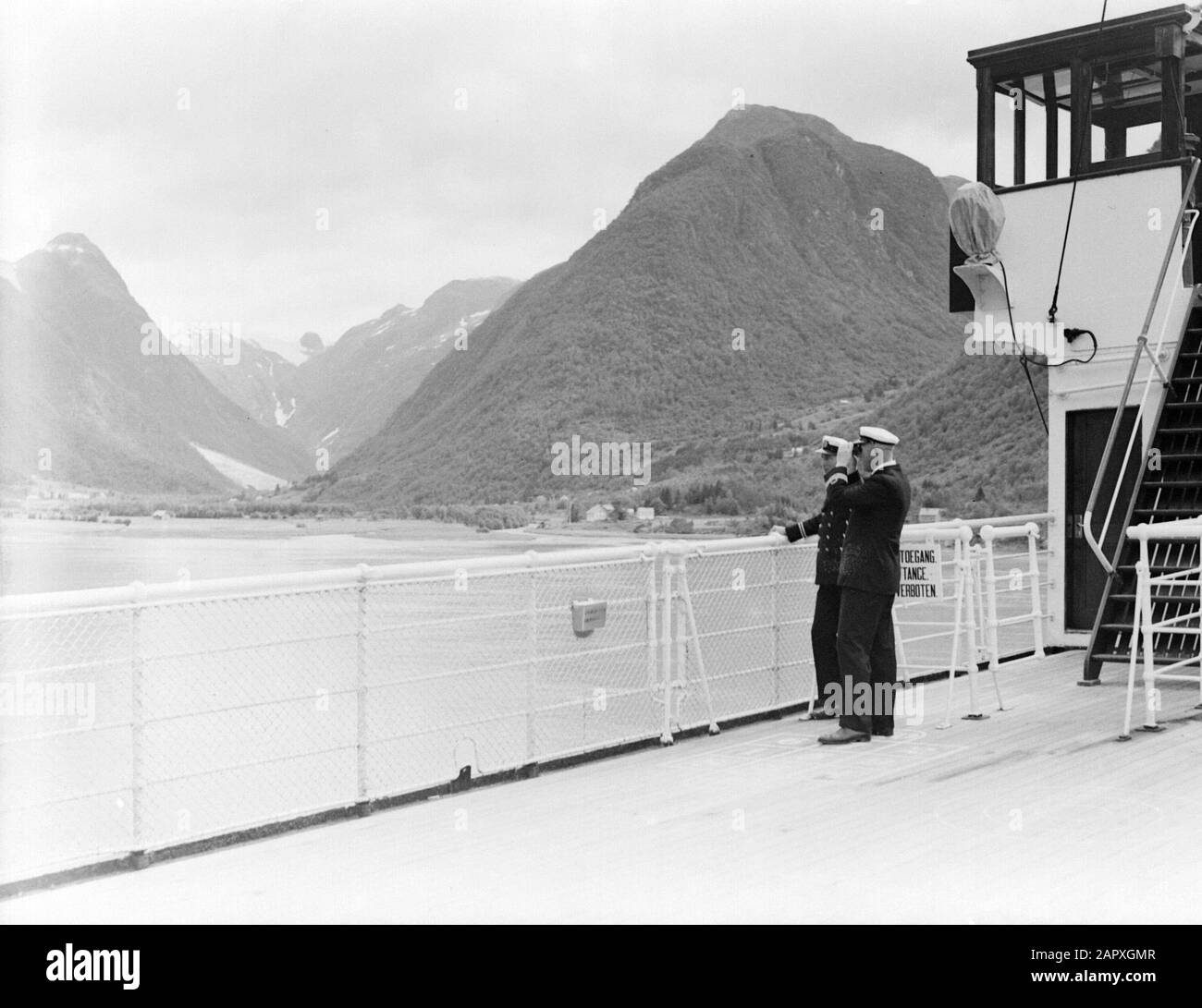 Sea voyage with MS Johan van Oldenbarnevelt to Norway  Sognefjord near Fjaerland. Two officers aboard the ship: with viewer the officer Leguit Date: 1933 Location: Fjaerland, Norway Keywords: mountains, cruises, cruise ships, fjords, fences, landscapes, officers, ships, tourism, binoculars Stock Photo