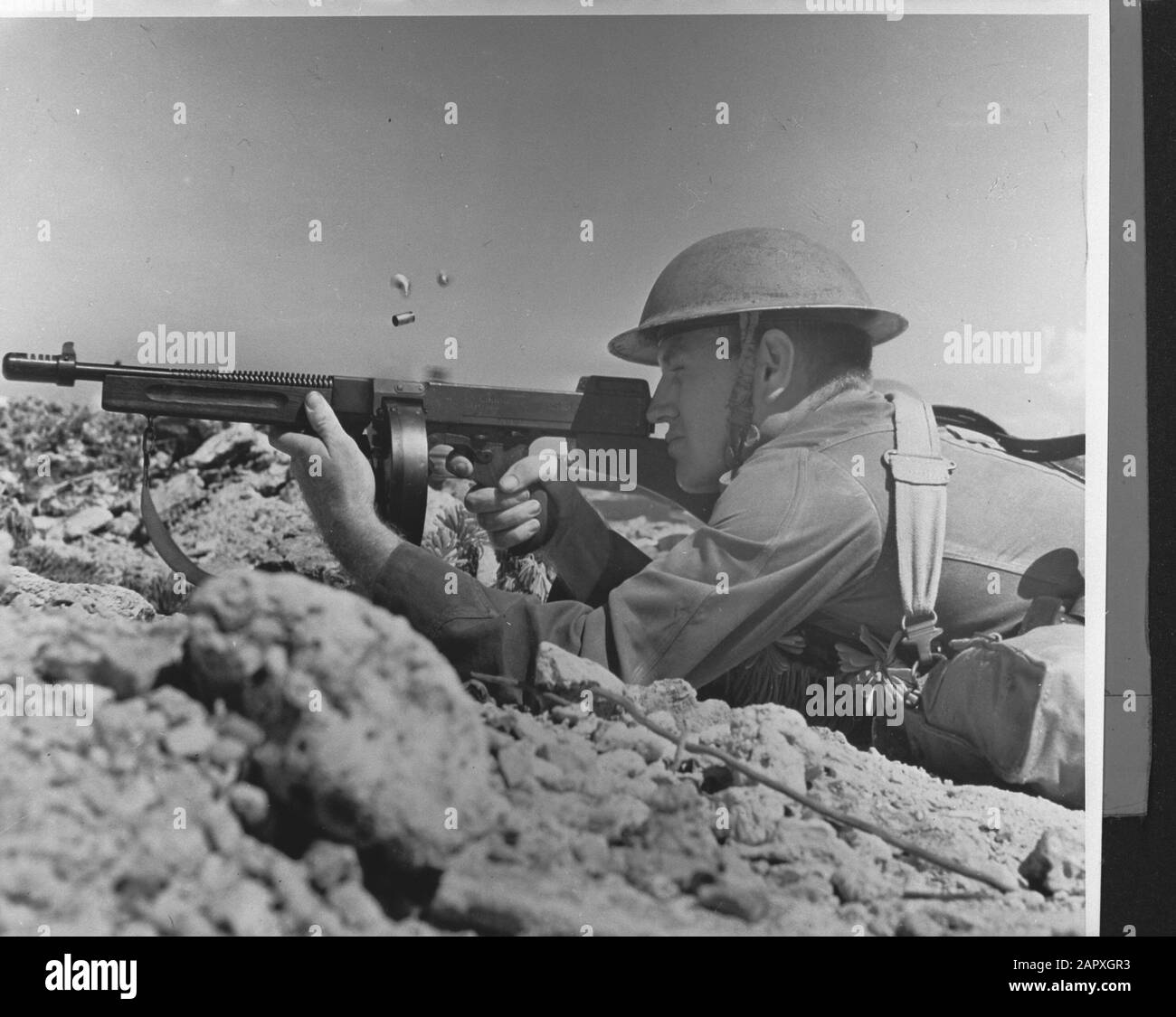 Wi [West Indies]/Anefo London series  Soldier of the Royal Netherlands Army with modern Tommy-gun on Curaçao's rocky coast [soldier of the Dutch army with a modern Tommy-gun on the rocky coast of Curaçao] Annotation: Repronegative. Date: {1940-1945} Location: Curaçao Keywords: army, machine guns, soldiers, World War II Stock Photo