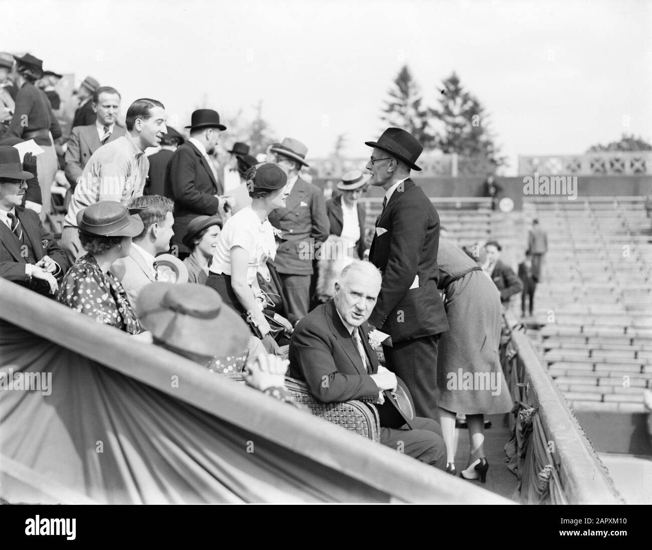 Reportage Paris Tennis match France-England at Roland Garros, English  ambassador (standing in hat) and Mr. and Mme Lacoste (both standing) Date:  May 1936 Location: Paris Keywords: diplomats, tennis, matches Personal  name: Lacoste,