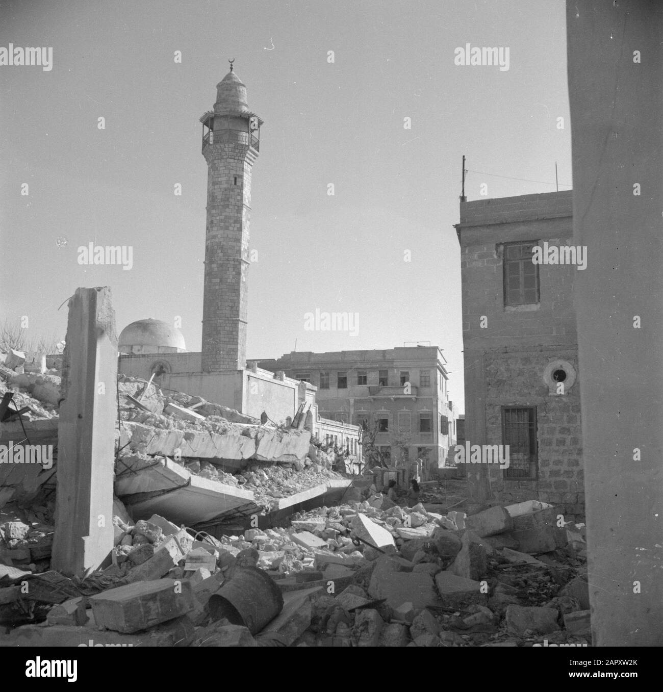 Israel 1948-1949: Jaffa  Destroyed building with the minaret of a mosque in the background Annotation: Jaffa was shot three days in 1948 by the Etsel (Irgoen), a Zionist militia in British Mandate area Palestine Date: 1948 Location: Israel, Jaffa Keywords: mosques, war damage, street statues, streets, towers Stock Photo