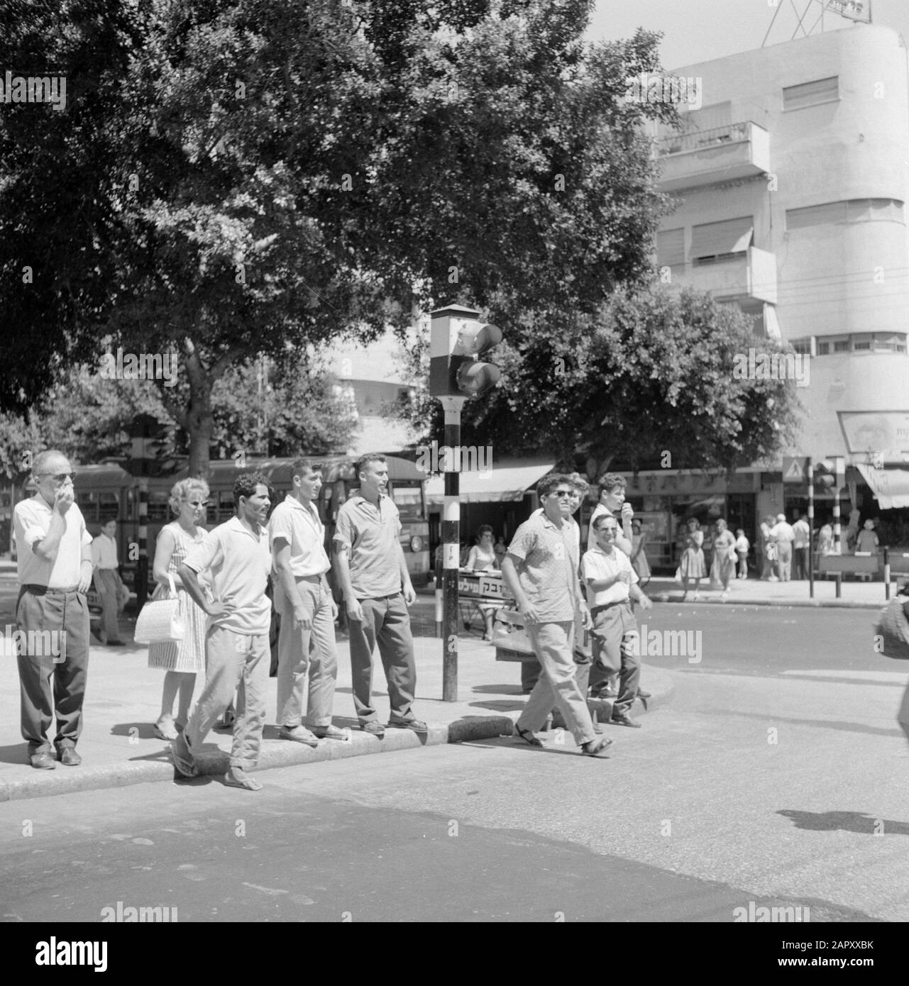 Israel 1964-1965: Tel Aviv, street images Pedestrians waiting for a traffic  light and making plans to cross at a pedestrian crossing Date: 1964  Location: Israel, Tel Aviv Keywords: daily life, handbag, slippers,