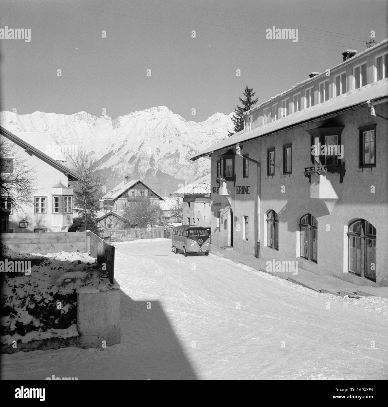 Winter in Tyrol  Volkswagen bus for Gasthaus Krone in Sistrans with in the background the Karwendel Mountains Date: January 1960 Location: Austria, Sistrans, Tyrol Keywords: cars, mountains, villages, hotels, snow, winter Stock Photo