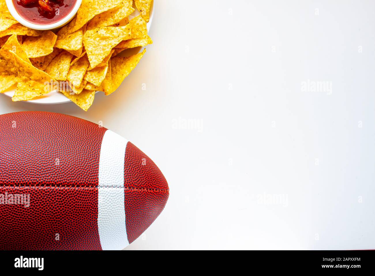 An American football with organic nacho chips and mild salsa on the side on a white background Stock Photo