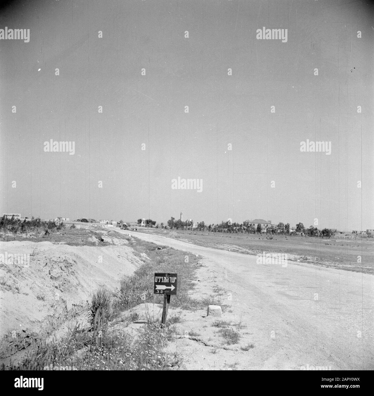 Israel 1948-1949: Negev Desert, Checkpoint  Road leading to a checkpoint in the Negev Desert, with a village in the background, presumably Beershewa Date: 1948 Location: Beersewa, Israel, Negev Keywords: signs, country roads, barriers, deserts Stock Photo