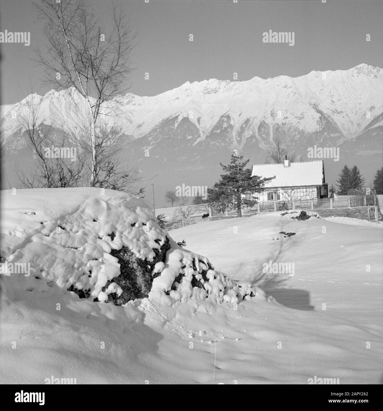 Winter in Tyrol  Property in the snow with the Karwendel Mountains in the background Date: January 1960 Location: Austria, Sistrans, Tyrol Keywords: mountains, landscapes, snow, winter, homes Stock Photo