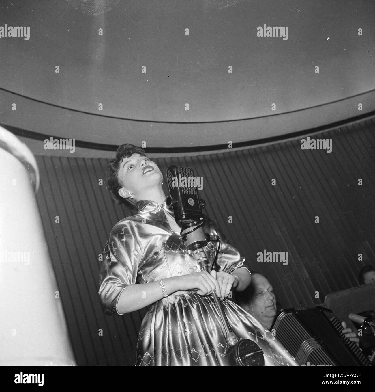 Restaurant Wivex located in the facade building of Tivoli Park  Singer in restaurant Wivex where a car show is held Date: March 1954 Location: Denmark, Copenhagen Keywords: cars, catering , microphones, restaurants, exhibitions, nightlife, singers Institution name: Wivex Stock Photo
