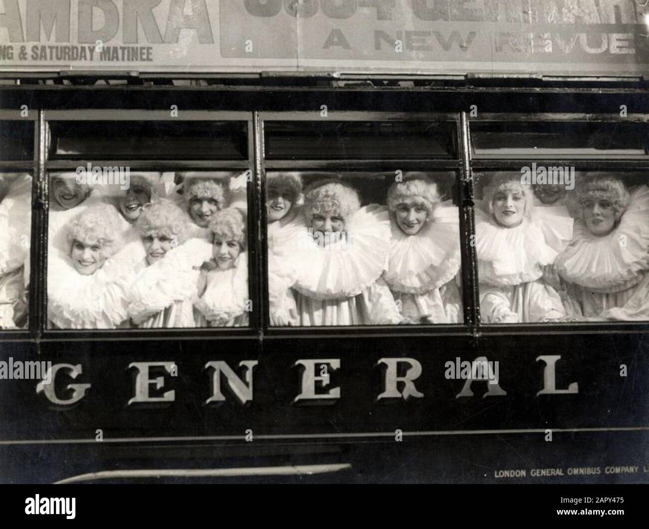 World War I: A group of English 'Pierrettes' with wigs and large white collars, looking smiling through the windows of a bus/tram. They raise money for war wounded. [England] ,1915. Stock Photo