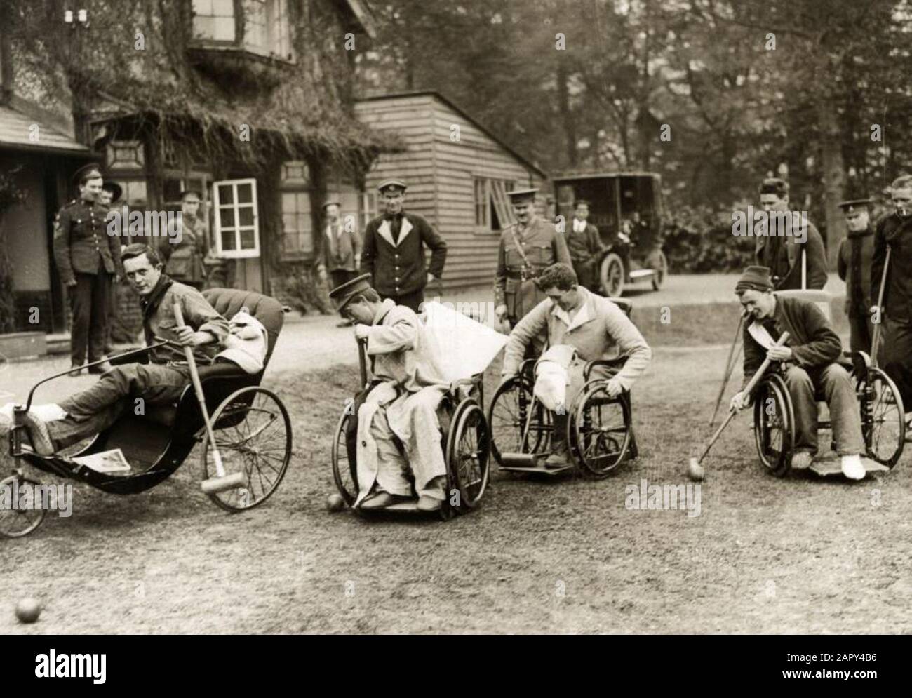 World War I. Disabled and wounded soldiers play sports from their  wheelchair. They enjoy playing a game of crocket and other soldiers watch  smiling. In the background a villa and trees. England,