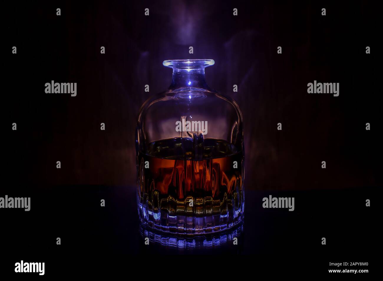 Decanter with whiskey on black background with blue light Stock Photo