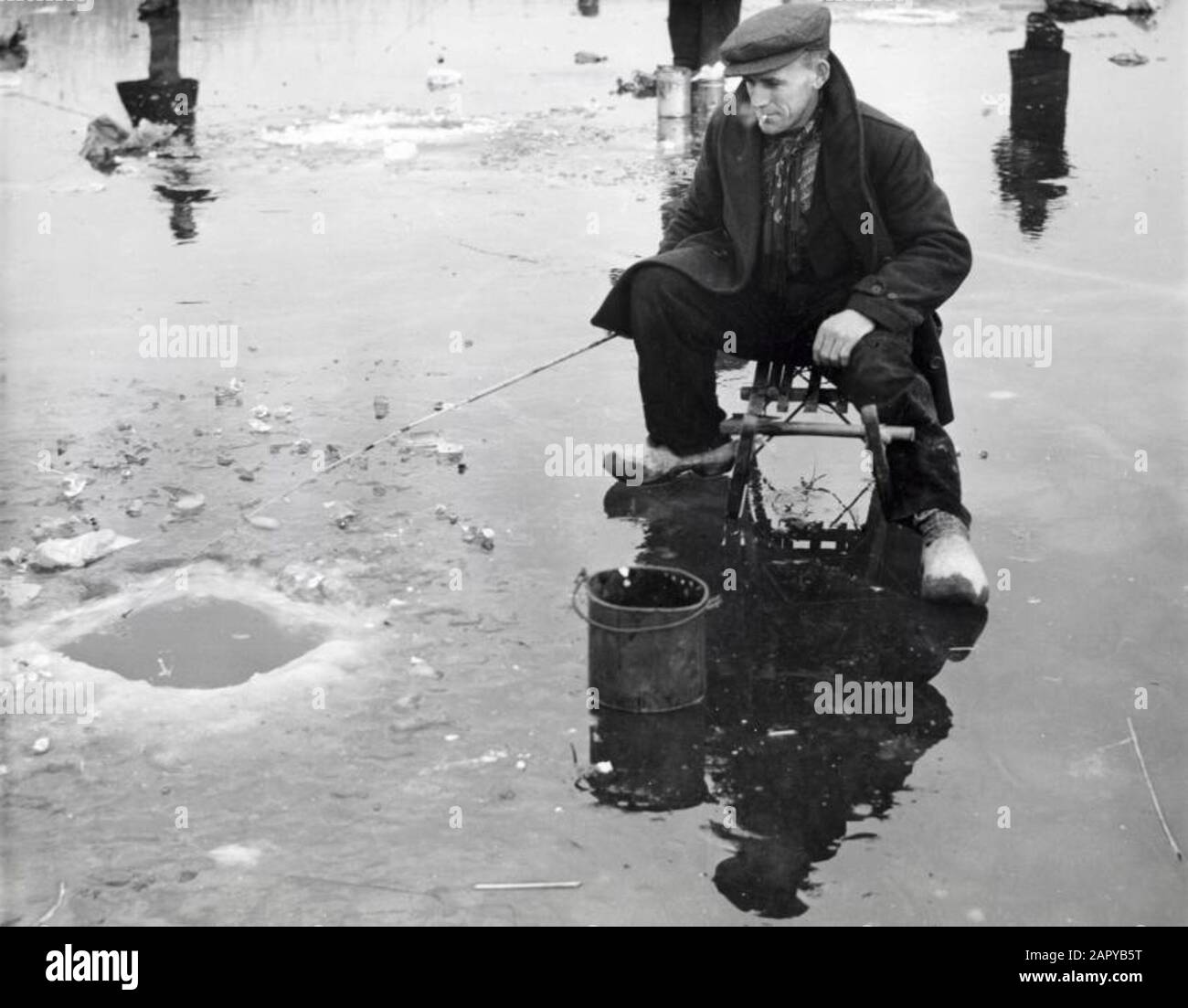 Ice fishing A man with clogs on sits on a sleigh on the ice in a wak fishing fishing the Netherlands without a year Stock Photo Alamy