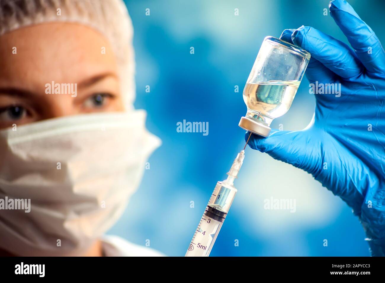 A doctor in medical gloves holding a bottle with vaccine and syringe before doing injection. Close up shot. Medicine and healthcare concept Stock Photo