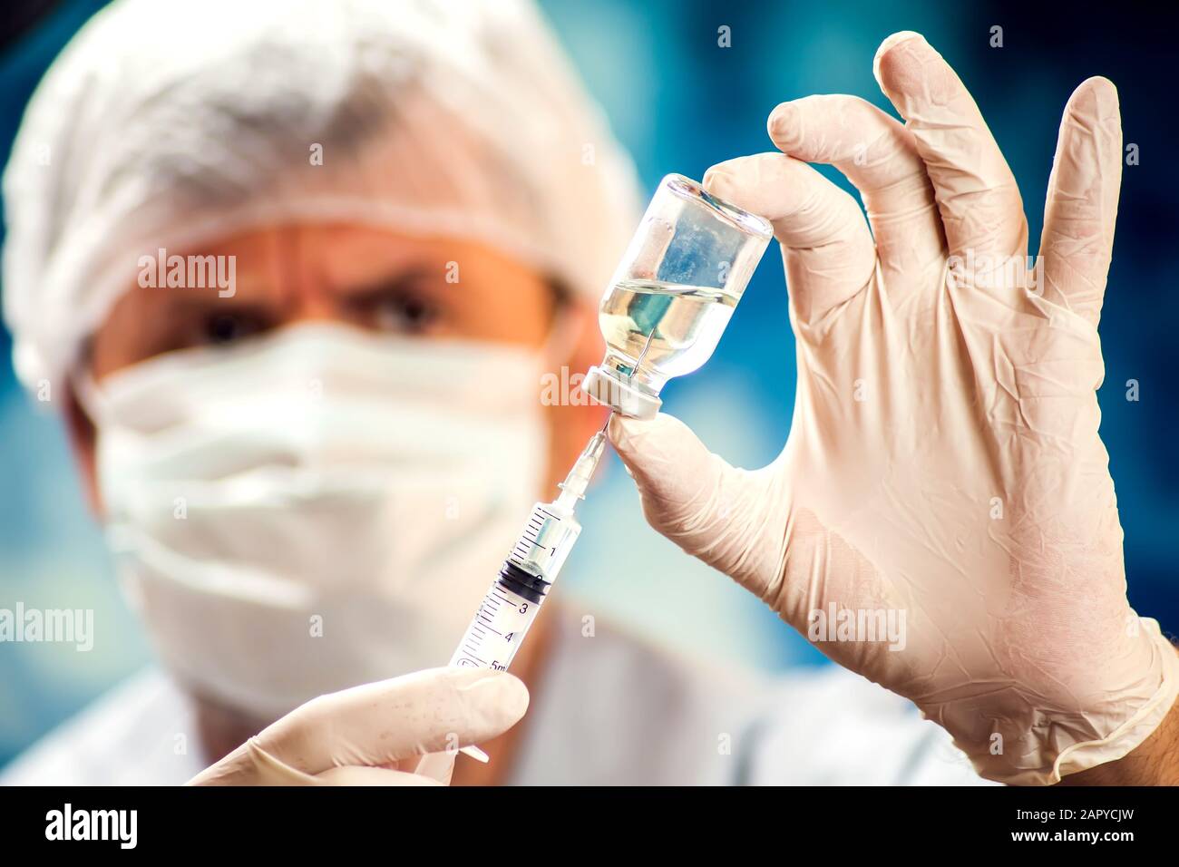 A doctor in medical gloves holding a bottle with vaccine and syringe before doing injection. Close up shot. Medicine, science and healthcare concept Stock Photo