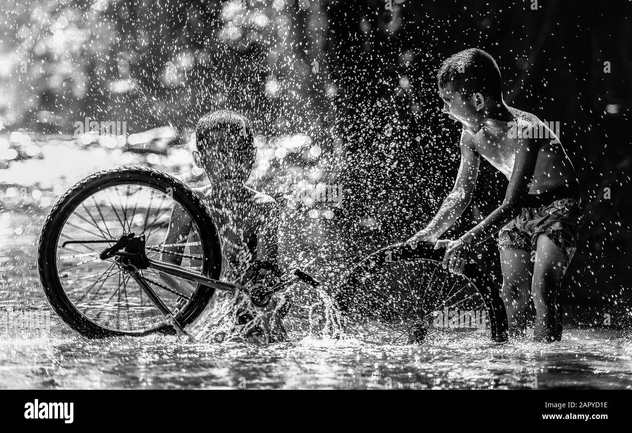 Two boy joyful with splashing from bicycle, Black and white tone Stock Photo