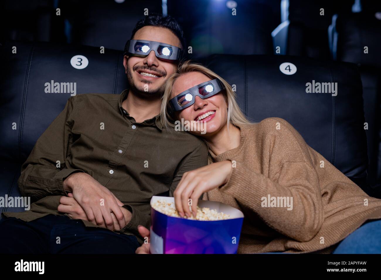 Happy young affectionate dates in 3d eyeglasses enjoying movie on large screen Stock Photo