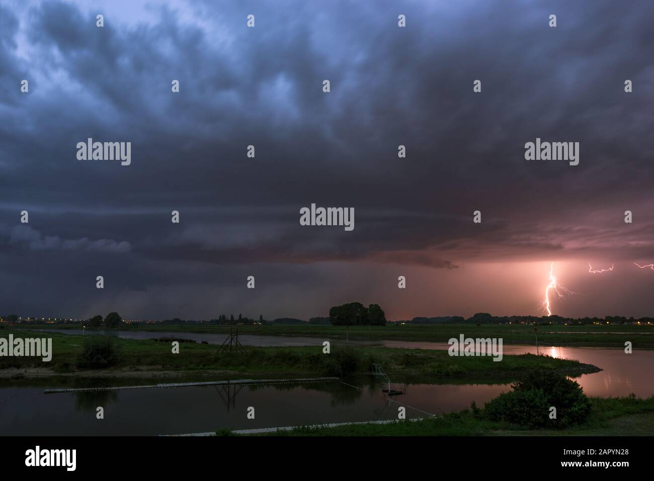 Shelfcloud and lightning from a severe thunderstorm near a river at dusk Stock Photo