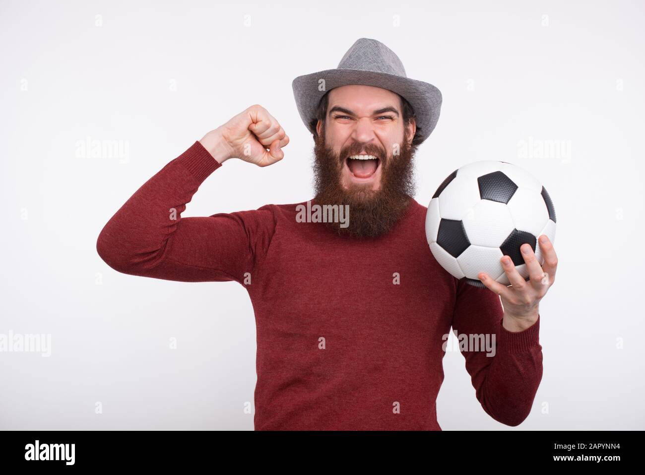 Young bearded man is screaming and holding a soccer ball. Stock Photo