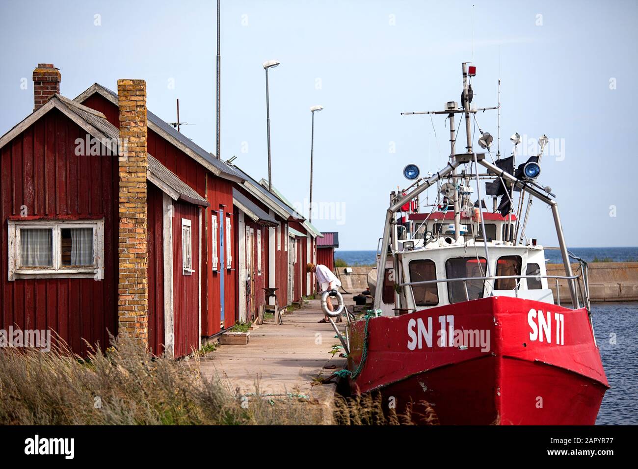 Red fishermen's cottages / rorbuer cabins and fishing boats in the small harbour of Graesgard / Gräsgård, Öland, Sweden Stock Photo