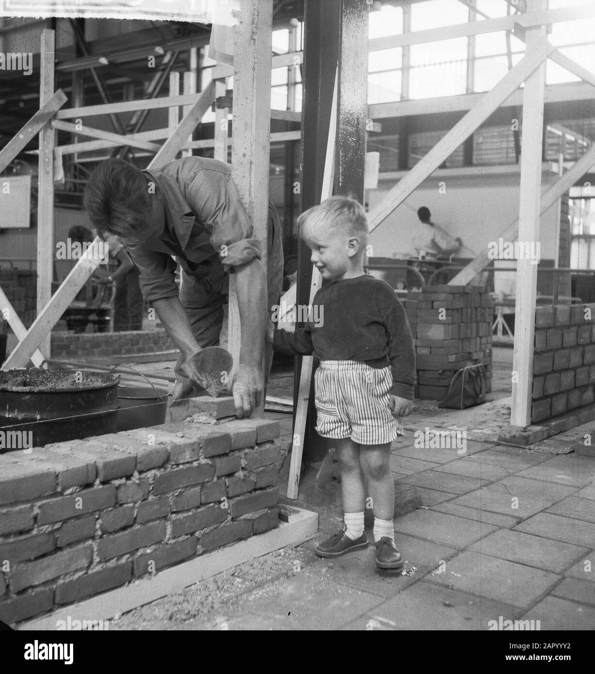 Masonry match at the Ahoy Hall. Little boy looks interested Date: July 5, 1961 Keywords: Bricklaying Setting name: Ahoy Stock Photo