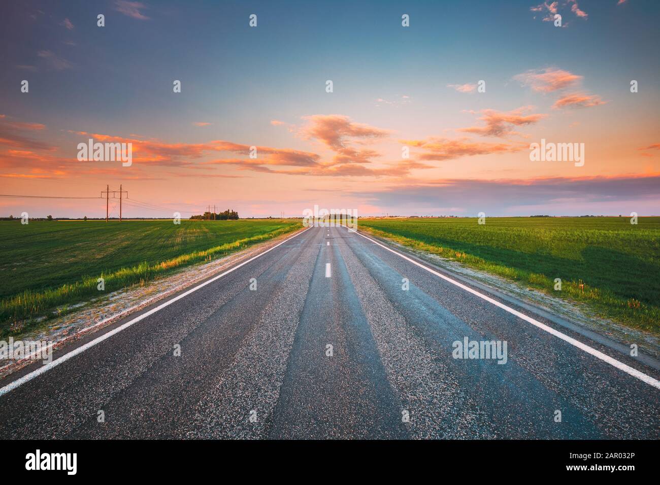 Asphalt Country Open Road Through Spring Fields And Meadows In Sunny Evening. Landscape In Early Summer Season At Sunny Sunset. Stock Photo