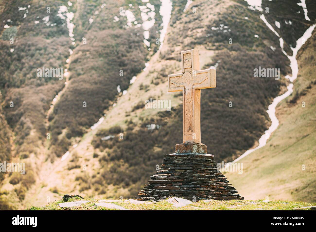 Gergeti, Georgia. Cross On A Pyramid Of Stones Near Gergeti Trinity Church Or Tsminda Sameba. Holy Trinity Church. Spring Or Summer Season. Stock Photo