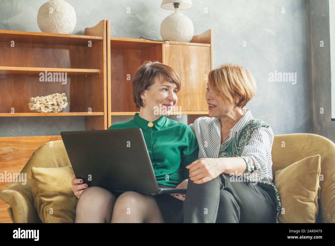 Happy mature women chatting and using laptop at home Stock Photo