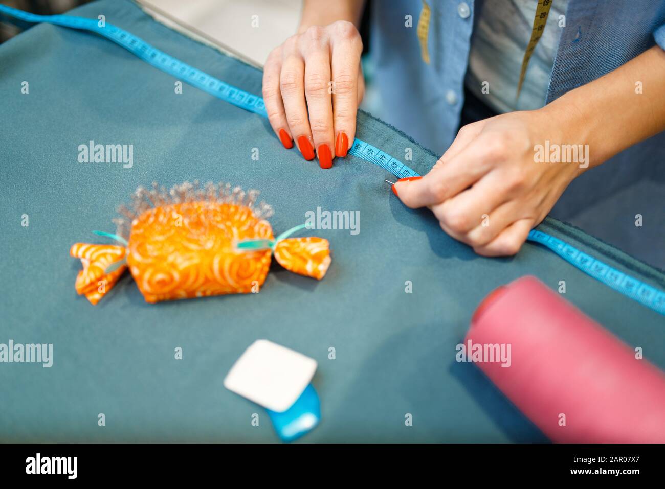 Seamstress measures fabric material, top view Stock Photo