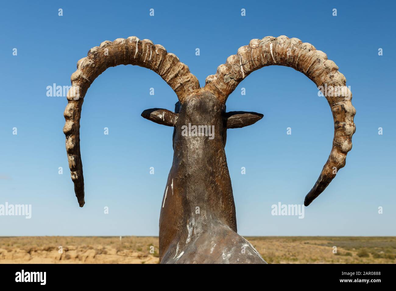 Statue of goat with curled horns with blue sky, back view Stock Photo ...