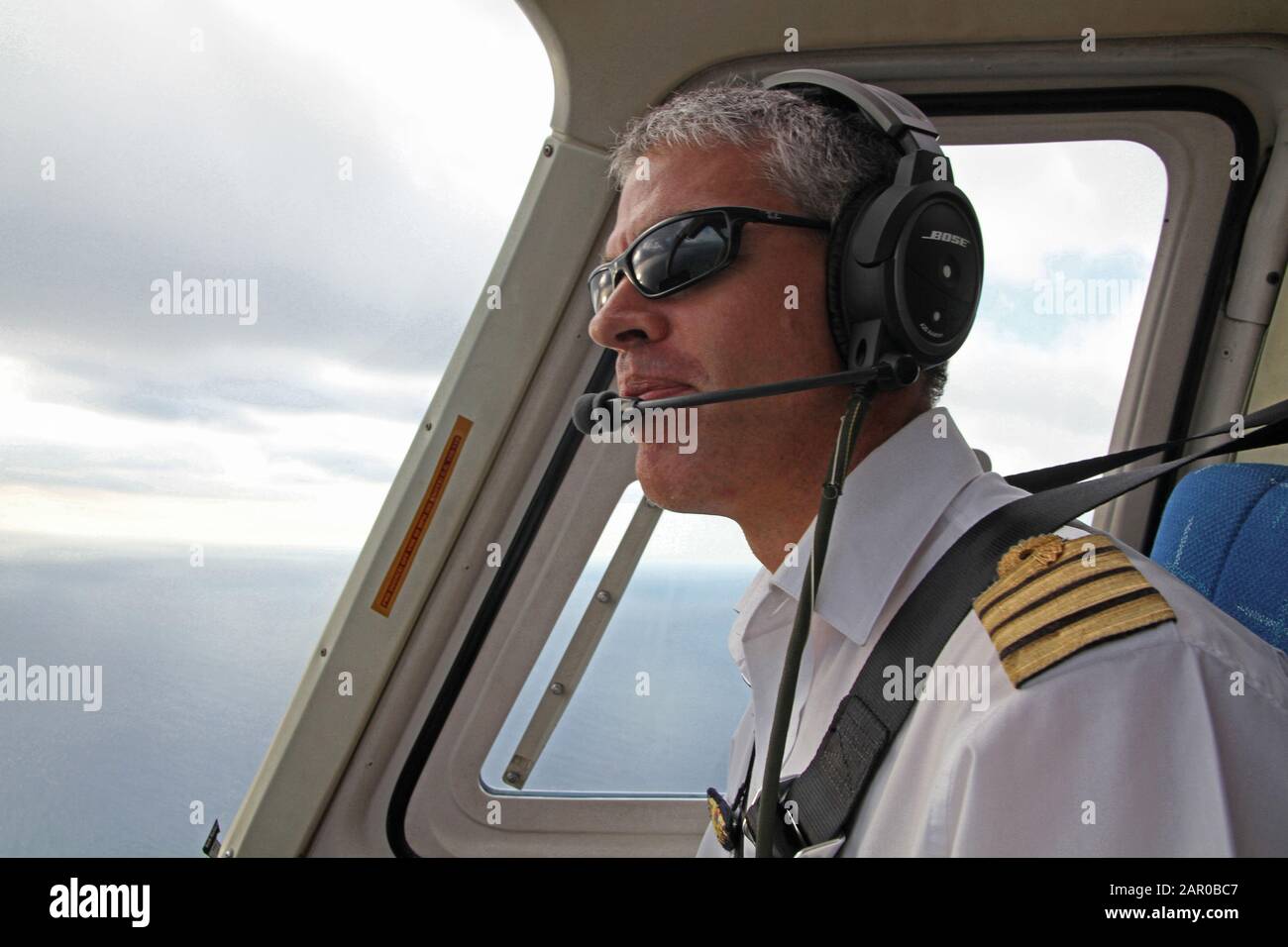 Pilot of a 3B-NZF Bell 206B JetRanger III tourist helicopter in flight, Mauritius. Stock Photo