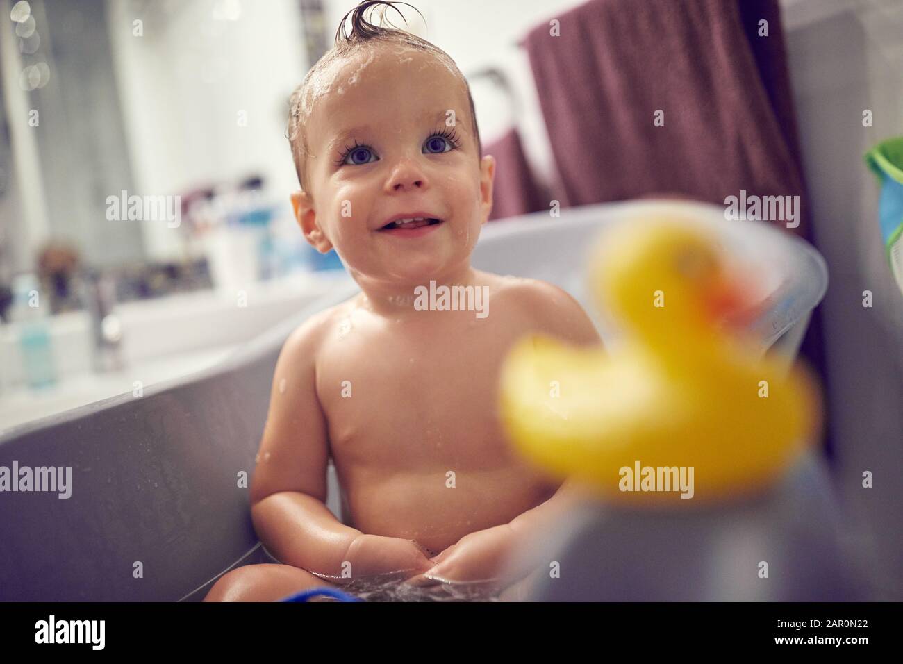 funny baby taking a bath playing with toys . Little child in a bathtub