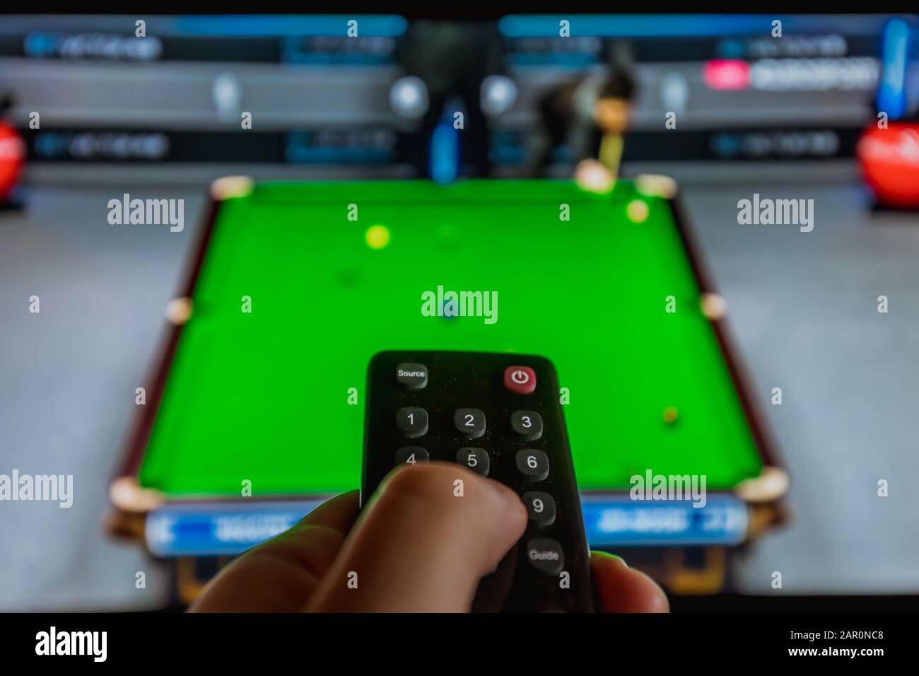 watching snooker at home tv with remote control in hand, entertainment Stock Photo