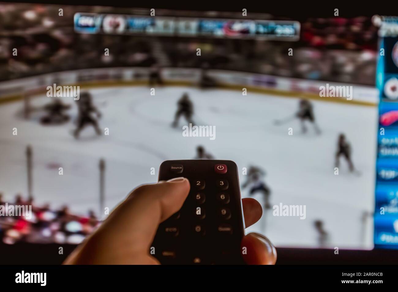 watching ice Hockey at home tv with remote control in hand, entertainment Stock Photo