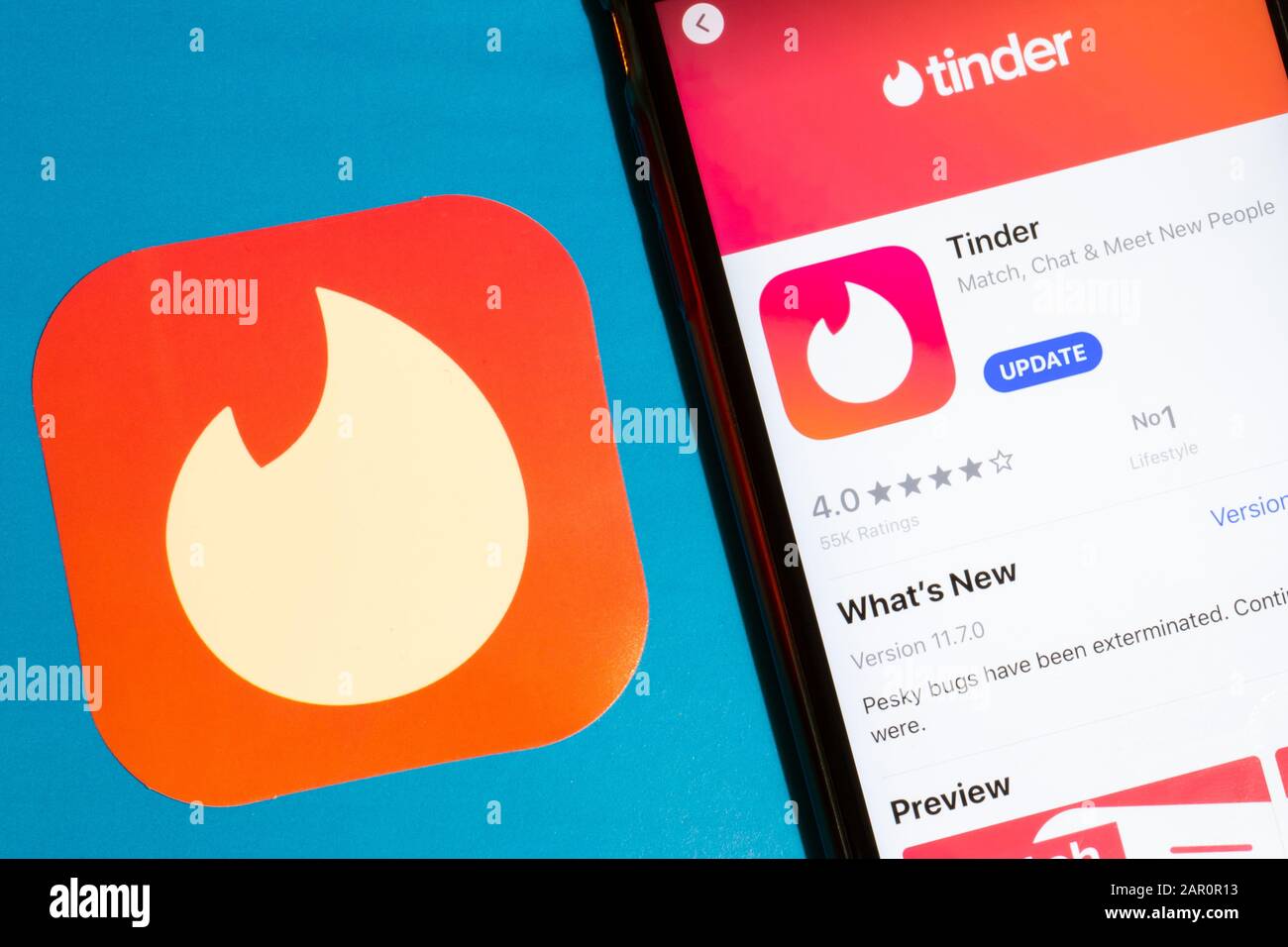 Los Angeles, California, USA - 22 January 2020: Tinder app logo and phone with icon close up on blue background, Illustrative Editorial Stock Photo