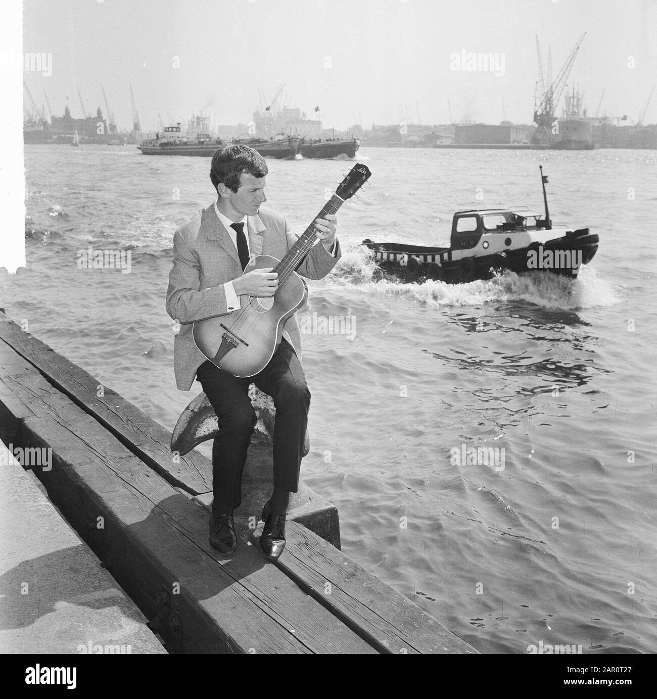 Gerard Cox in tv show of NCRV, singer Dutch chanson here at the port of Rotterdam Date: May 20, 1964 Location: Rotterdam, Zuid-Holland Keywords: TV shows, guitars, harbours, singers Personal name: Cox, Gerard Stock Photo