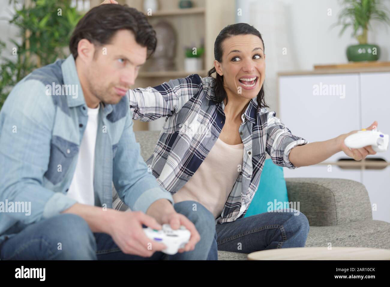 woman beating her boyfriend while playing video games Stock Photo