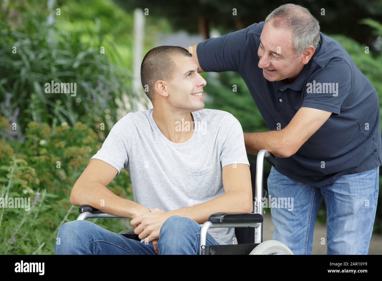 father pushing handicapped sons wheelchair Stock Photo Alamy