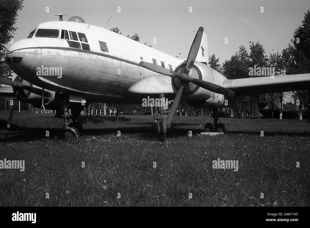 STUPINO, MOSCOW REGION, RUSSIA - CIRCA 1992: A soldier of the Russian army on the background of a Soviet twin-engine military cargo transport aircraft Ilyushin Il-14. Black and white. Film scan. Large grain. Stock Photo