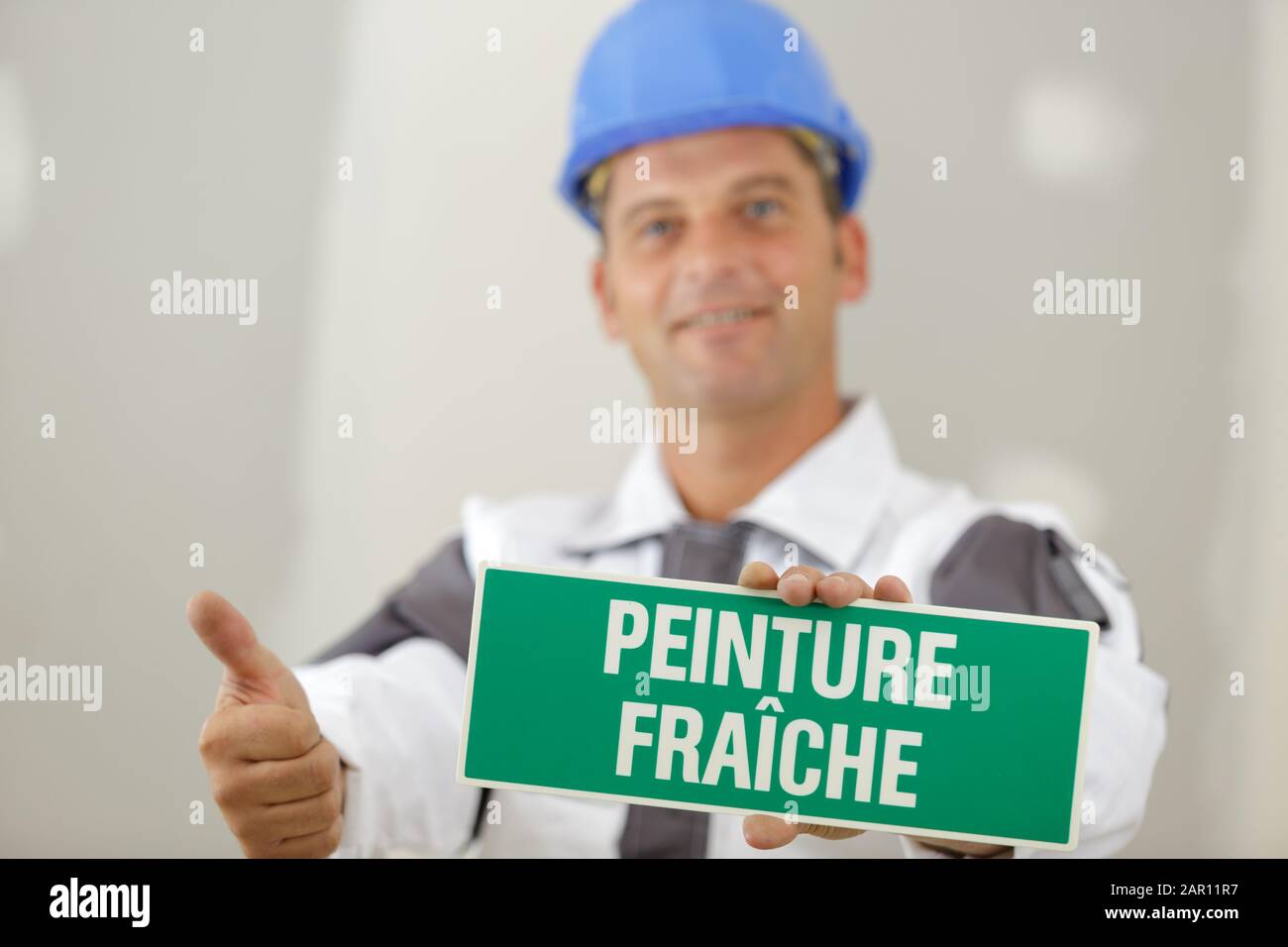 a male builder shows caution wet paint Stock Photo Alamy
