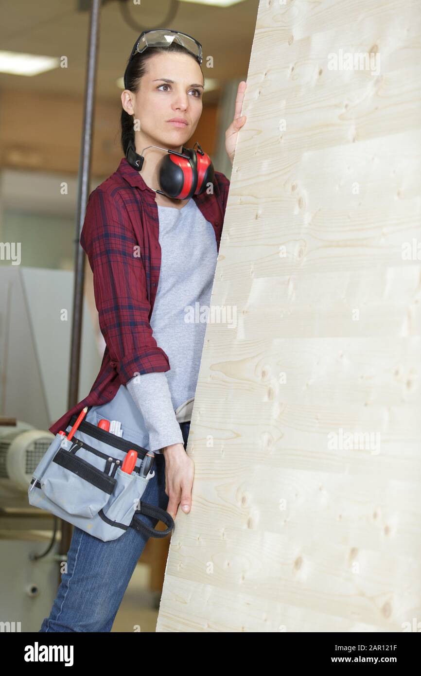 female carpenter carrying sheet of wood Stock Photo
